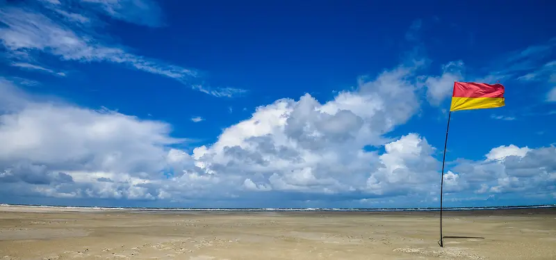 清新摄影蓝天白云海滩上插着一面红黄两色的旗帜