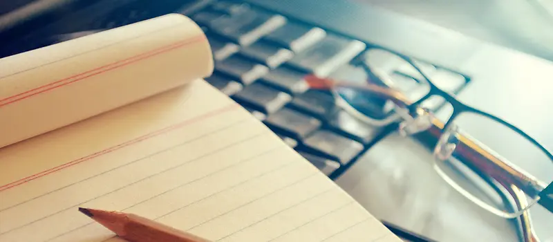 文艺商务摄影电脑键盘上的纸笔与眼镜